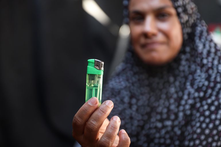 Rabab Deifallah holds the lighter she relies on to cook, bake bread and heat water for her five children [Abdelhakim Abu Riash/ Al Jazeera]