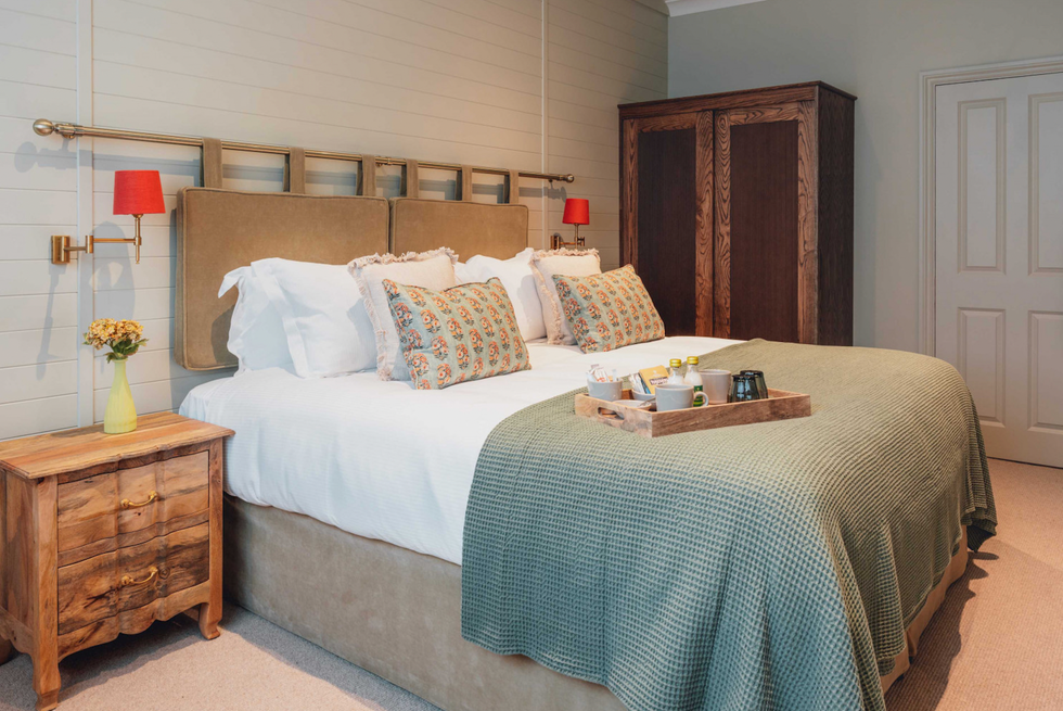 The Ropemaker cozy bedroom with double bed, floral pillows, and a wooden tray with breakfast items.