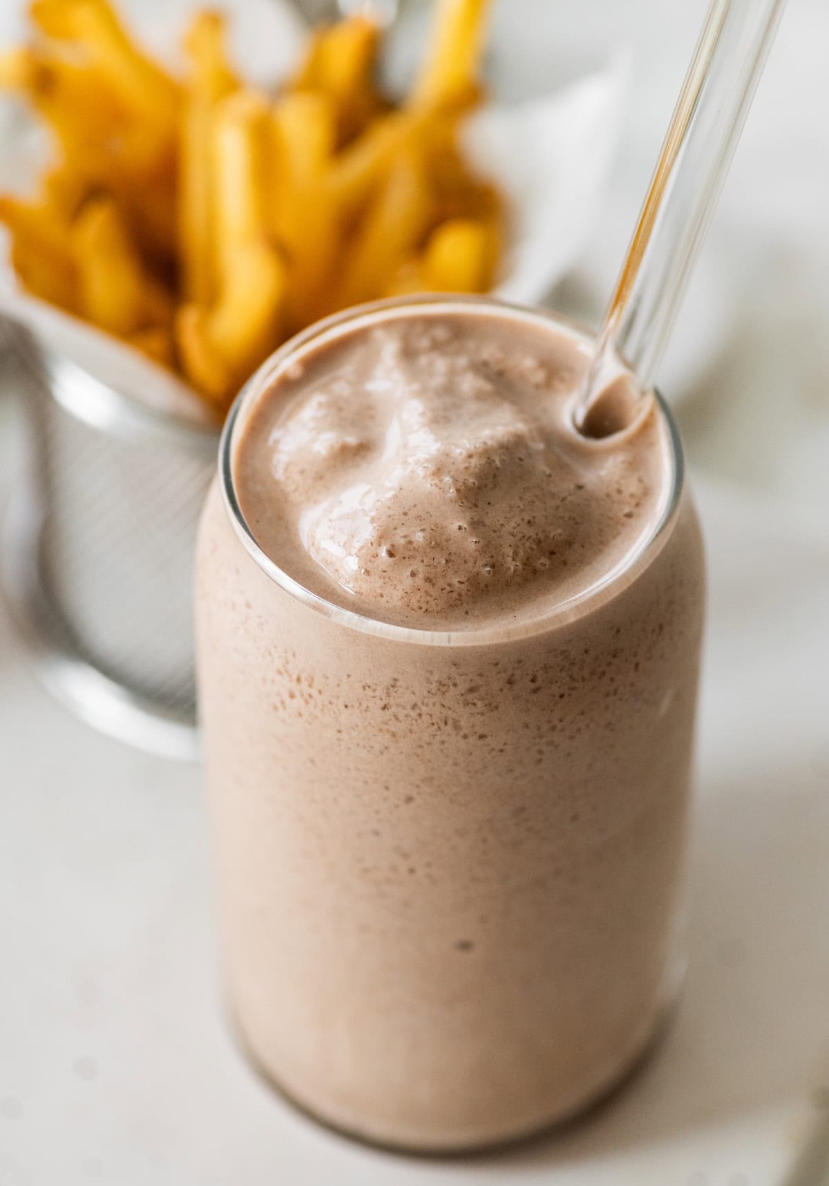 A high protein copycat Wendy's frosty in a tall glass cup with a glass straw.