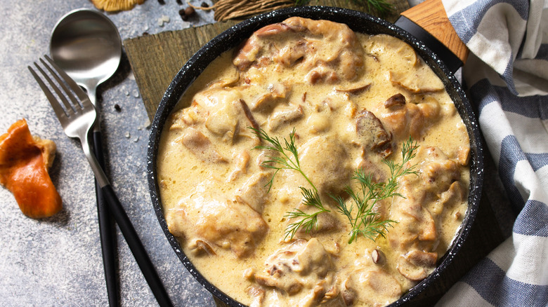 A pan of chicken fricassée with a fork and a spoon.