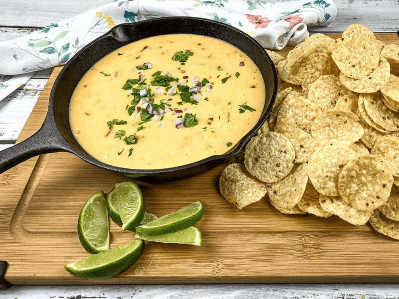 Velveeta queso in a skillet with tortilla chips and lime wedges.