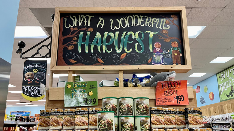 Chalkboard sign reading "what a wonderful harvest" above Trader Joe's seasonal fall item display
