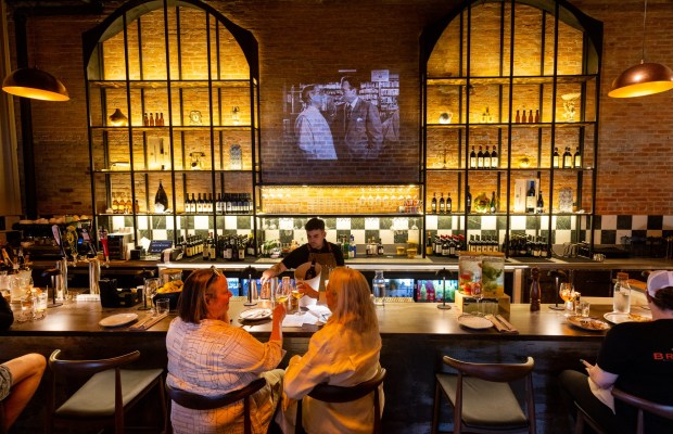 The bar with old movies shown on the brick wall at the new second location for L'Oro di Napoli Friday, February 28, 2025 in Petaluma. (John Burgess / The Press Democrat)